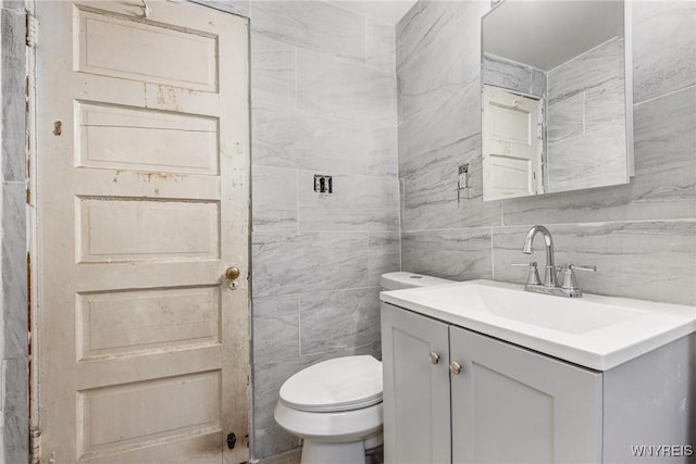 bathroom with vanity, decorative backsplash, tile walls, and toilet