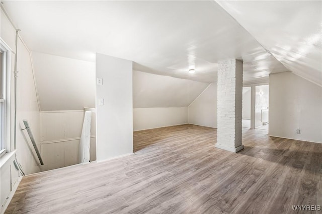 additional living space featuring decorative columns, lofted ceiling, and hardwood / wood-style floors