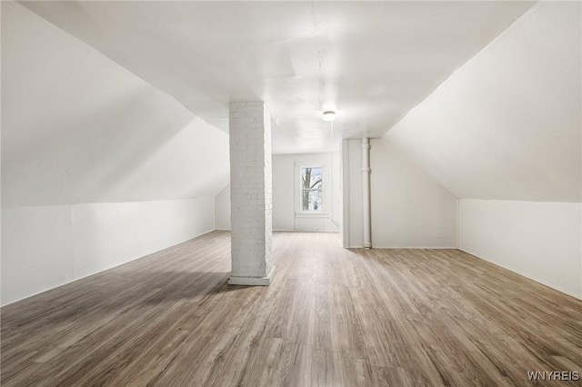 additional living space with wood-type flooring, ornate columns, and vaulted ceiling