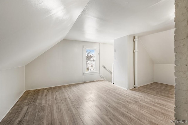 additional living space featuring lofted ceiling and light hardwood / wood-style flooring