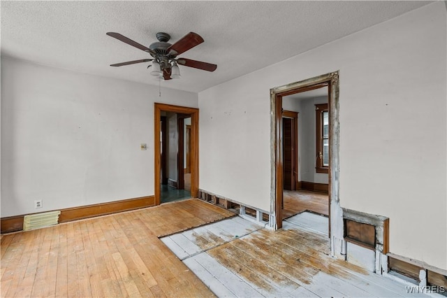 unfurnished room with ceiling fan, a textured ceiling, and light wood-type flooring