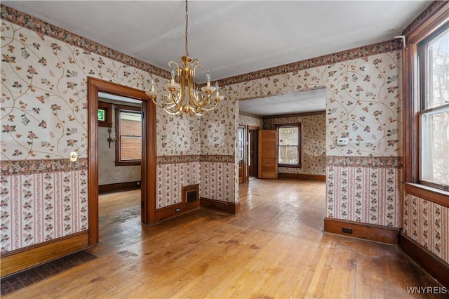 unfurnished dining area with hardwood / wood-style floors and a chandelier