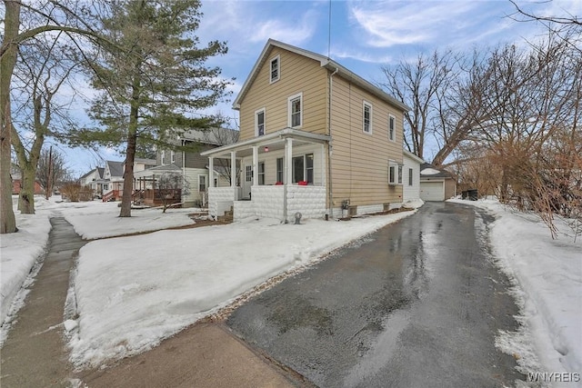 view of front of house featuring aphalt driveway, a detached garage, a porch, and an outdoor structure