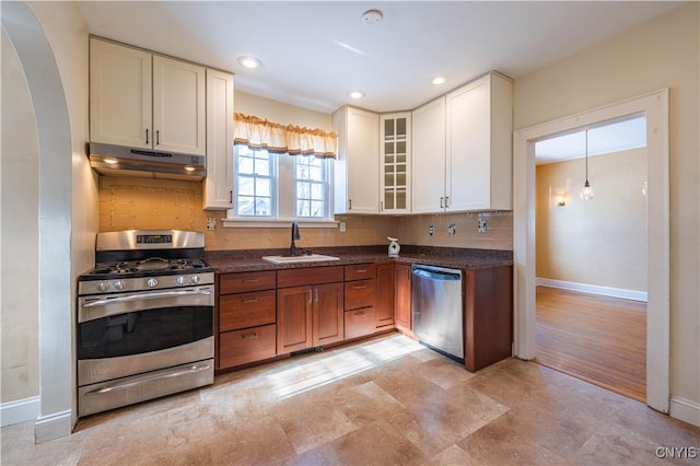 kitchen with sink, white cabinetry, backsplash, stainless steel appliances, and dark stone counters