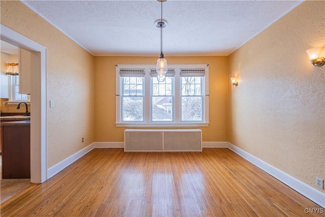 unfurnished dining area with hardwood / wood-style flooring, radiator, and a textured ceiling