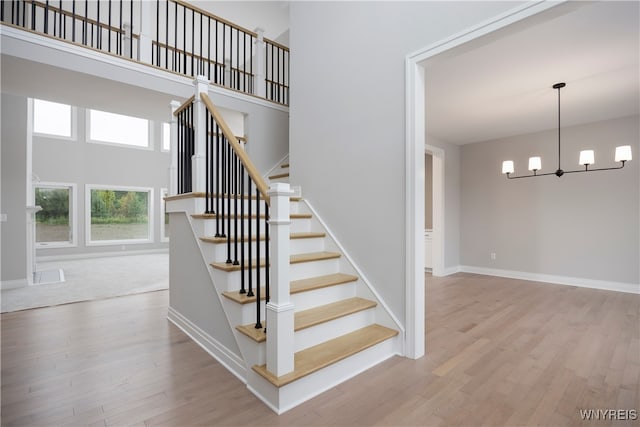 staircase featuring hardwood / wood-style floors, a chandelier, and a high ceiling