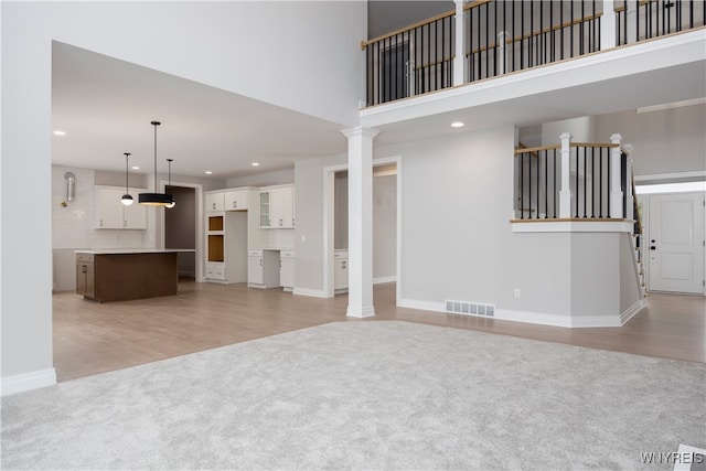 60 Woodthrush Trl, Orchard Park, NY 14127 - unfurnished living room featuring decorative columns, a high ceiling, and light colored carpet