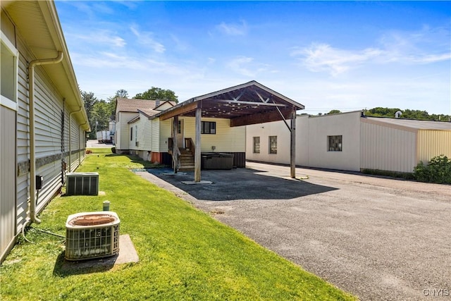 back of property featuring central AC and a lawn