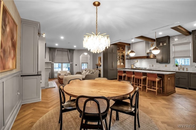 dining space featuring sink, beam ceiling, and light parquet flooring