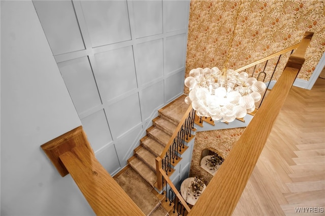 stairs with an inviting chandelier and parquet flooring