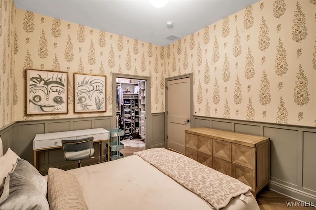 bedroom with parquet floors, a walk in closet, and a closet