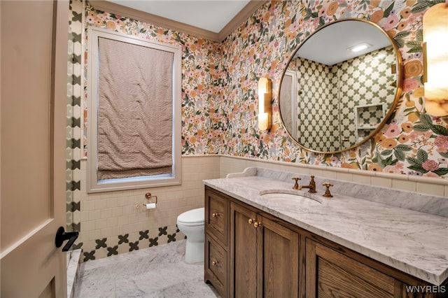 bathroom with crown molding, vanity, toilet, and tile walls