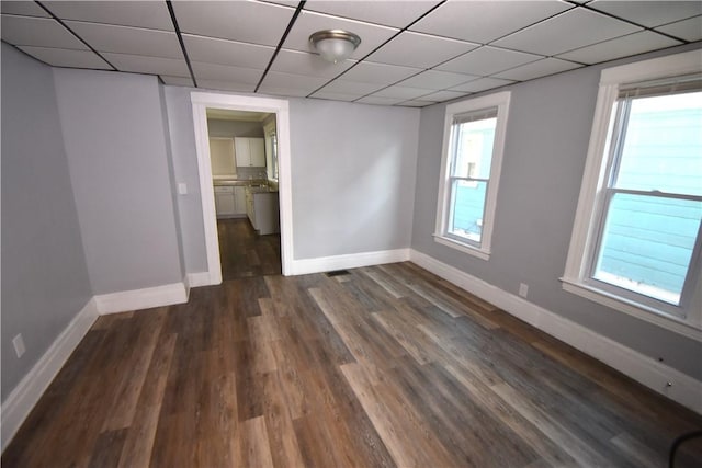 spare room featuring a healthy amount of sunlight, a paneled ceiling, and dark hardwood / wood-style flooring