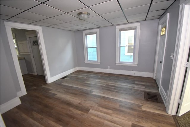 empty room featuring a paneled ceiling and dark hardwood / wood-style floors