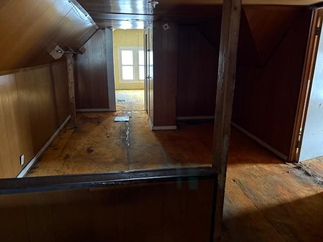 interior space featuring lofted ceiling and wooden walls