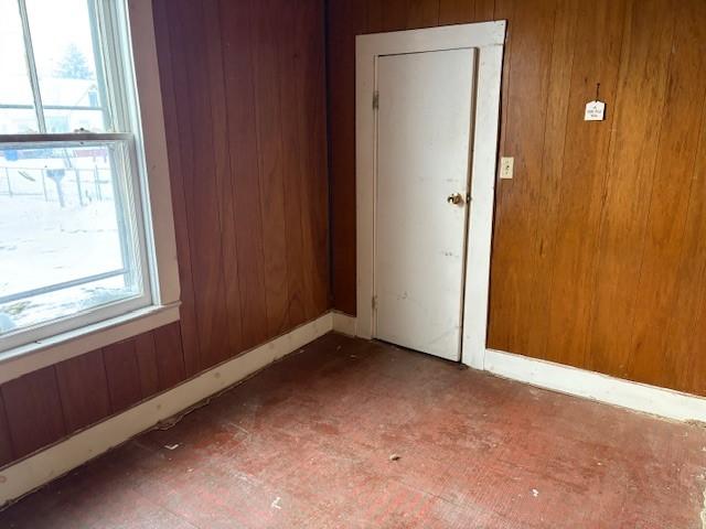 empty room featuring a wealth of natural light and wooden walls