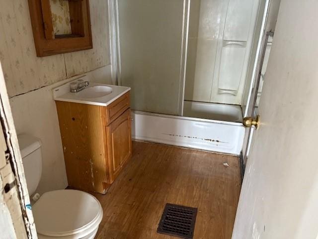 full bathroom featuring hardwood / wood-style flooring, vanity, toilet, and combined bath / shower with glass door