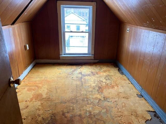 additional living space featuring lofted ceiling and wood walls