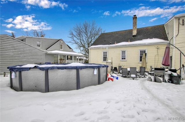 snow covered rear of property with a covered pool