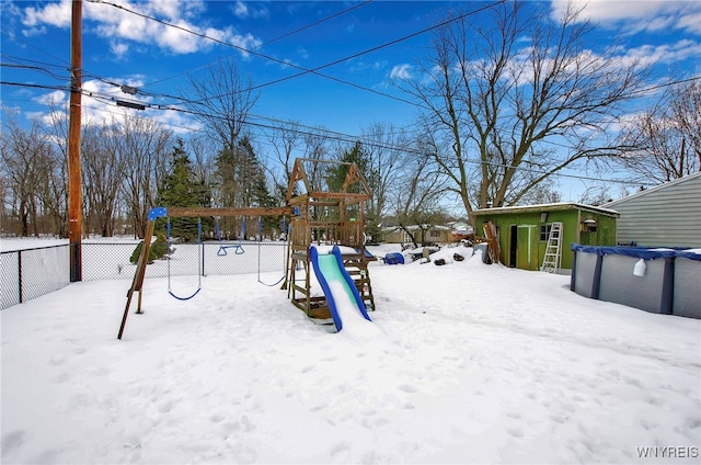 yard covered in snow featuring a playground