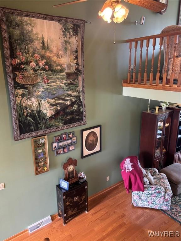 living room with visible vents, baseboards, a ceiling fan, and wood finished floors