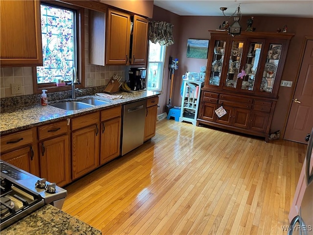 kitchen featuring light wood-type flooring, appliances with stainless steel finishes, decorative backsplash, and a sink