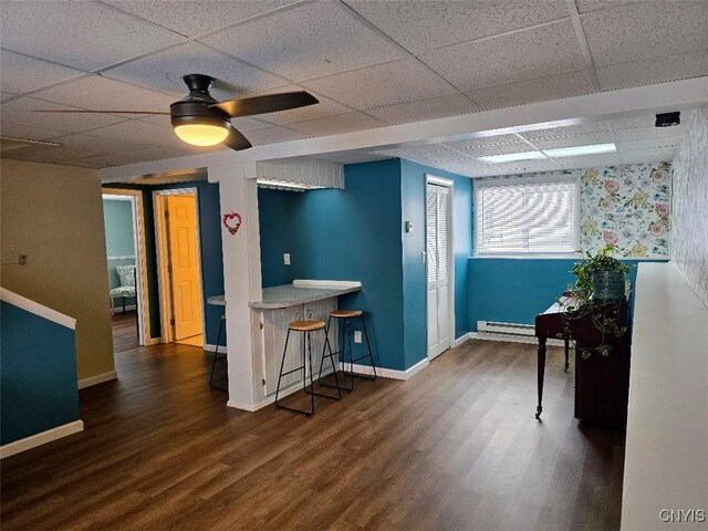 kitchen featuring dark hardwood / wood-style flooring, a paneled ceiling, and a kitchen breakfast bar