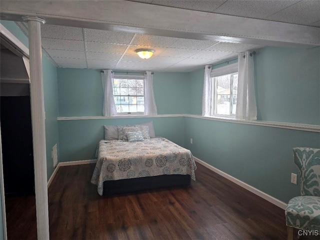 bedroom with dark hardwood / wood-style floors, multiple windows, and a drop ceiling