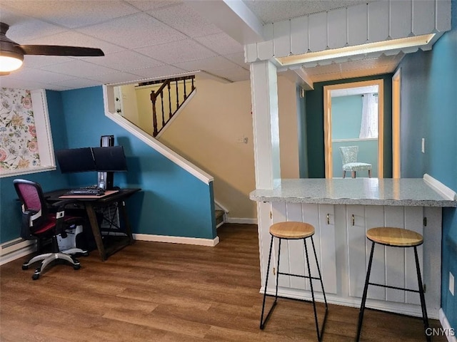 interior space with hardwood / wood-style floors, a drop ceiling, and ceiling fan