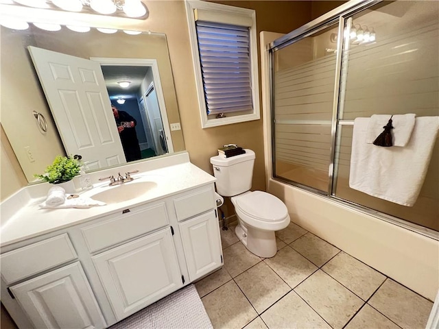 full bathroom with tile patterned flooring, vanity, bath / shower combo with glass door, and toilet