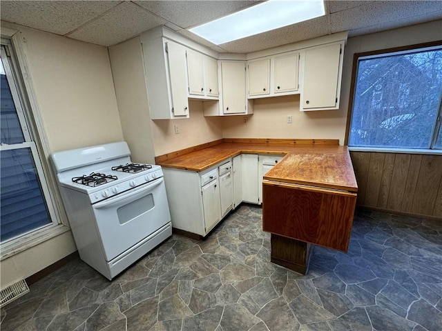 kitchen with white cabinets, wooden counters, white gas stove, and a drop ceiling