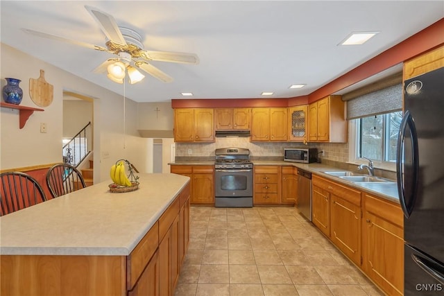 kitchen with ceiling fan, appliances with stainless steel finishes, a center island, light tile patterned flooring, and decorative backsplash