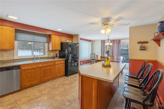 kitchen with sink, black fridge, dishwasher, a kitchen island, and backsplash