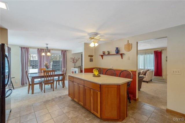 kitchen featuring light carpet, hanging light fixtures, black refrigerator, baseboard heating, and a kitchen island