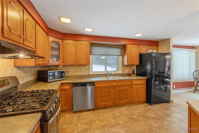 kitchen with sink, light tile patterned floors, appliances with stainless steel finishes, decorative backsplash, and a baseboard radiator