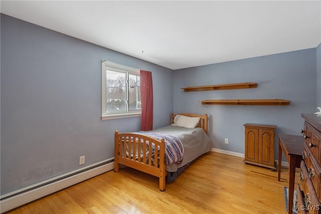 bedroom with a baseboard heating unit and light hardwood / wood-style floors