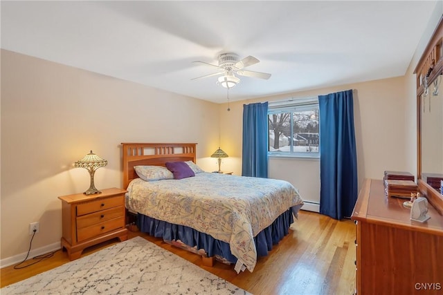 bedroom featuring ceiling fan, light wood-type flooring, and baseboard heating