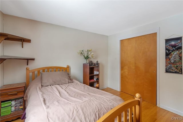 bedroom with light hardwood / wood-style floors and a closet