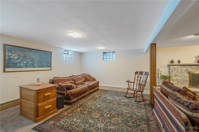 living room with baseboard heating, a stone fireplace, and dark colored carpet