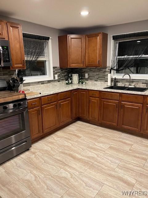 kitchen with stainless steel appliances, light stone countertops, sink, and backsplash