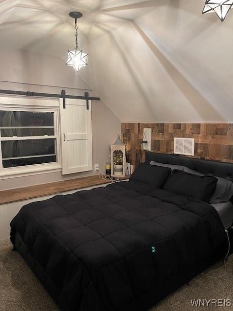 bedroom featuring vaulted ceiling, a barn door, and wood walls