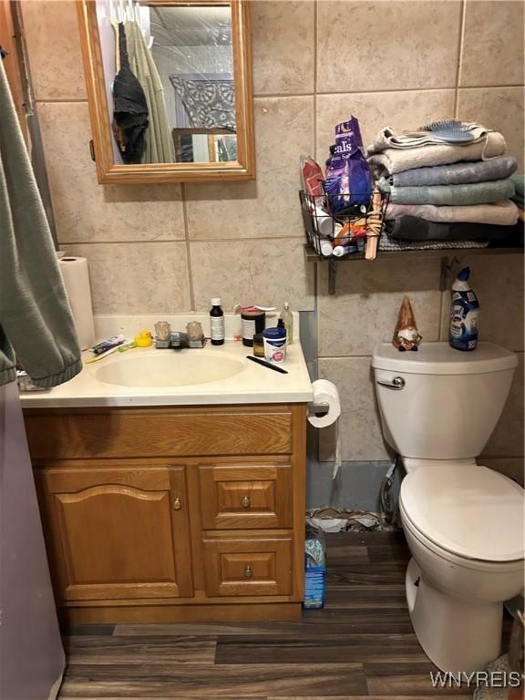 bathroom featuring toilet, tile walls, and vanity