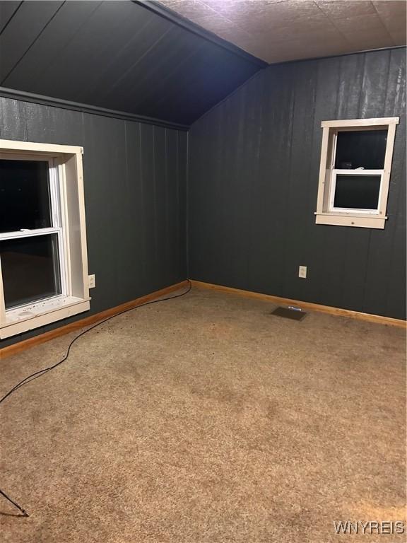 unfurnished room featuring carpet floors, vaulted ceiling, and baseboards