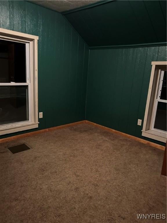 bonus room featuring vaulted ceiling, carpet floors, wood walls, and visible vents