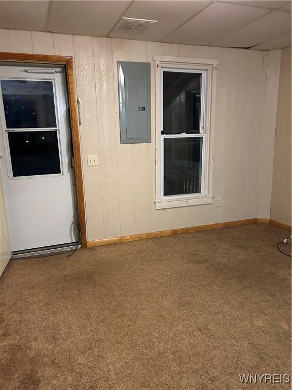 unfurnished room with electric panel, wood walls, and baseboards