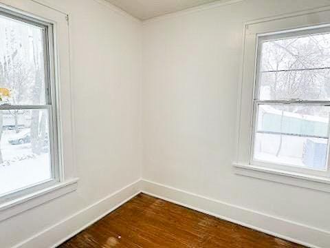 empty room with dark wood-type flooring and crown molding