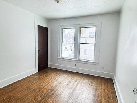 unfurnished room with dark hardwood / wood-style flooring and a textured ceiling