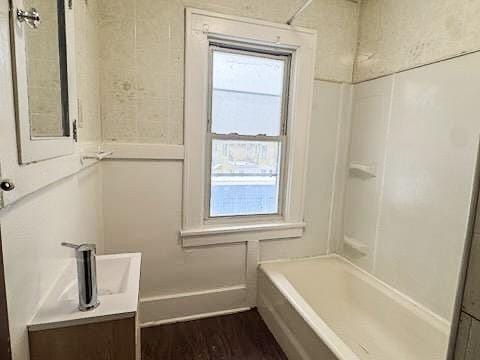 bathroom featuring hardwood / wood-style flooring, vanity, a wealth of natural light, and bathing tub / shower combination