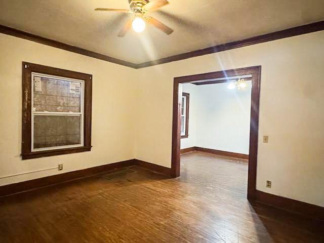 unfurnished room featuring crown molding, dark wood-type flooring, and ceiling fan