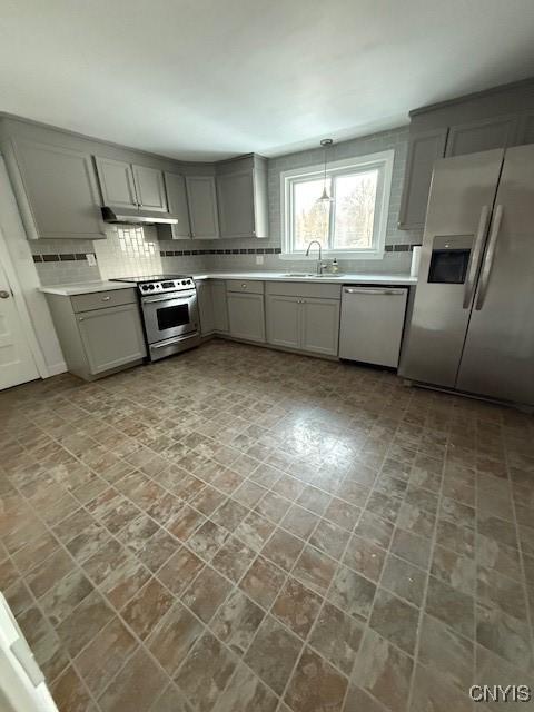 kitchen featuring sink, decorative light fixtures, gray cabinets, stainless steel appliances, and backsplash